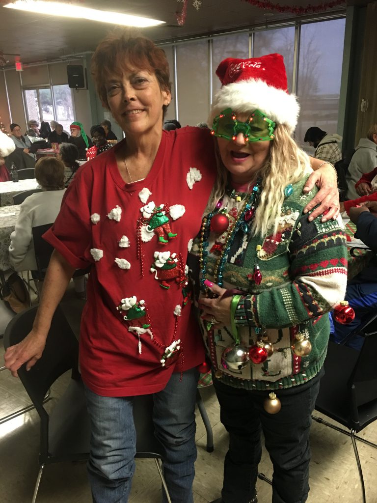 Linda Miller and Julie Atkins model their Christmas sweaters in advance of the contest at the annual Christmas Bingo Blitz at Love Towers on Dec. 19